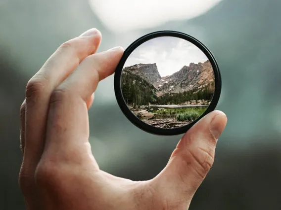 Hand holding a magnifying glass.