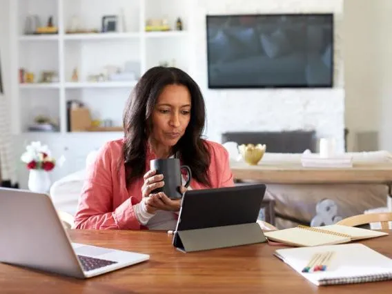 Woman drinking coffee looks at tablet