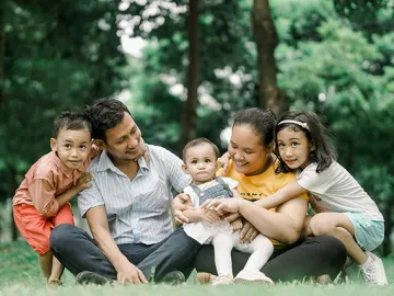 A family of 5 sitting outside on the grass together